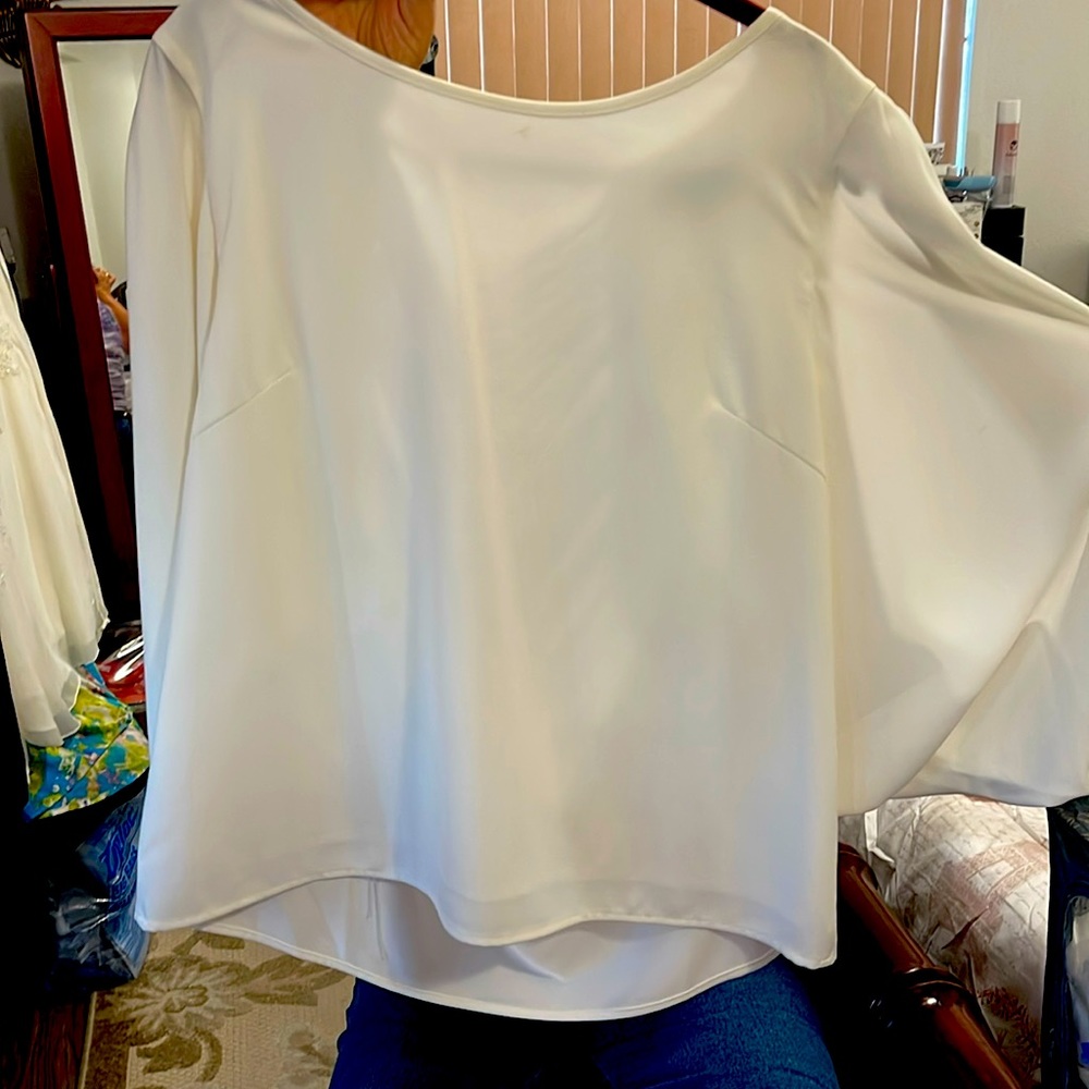 Cream polyester and spandex top. Flowing arm with slits.